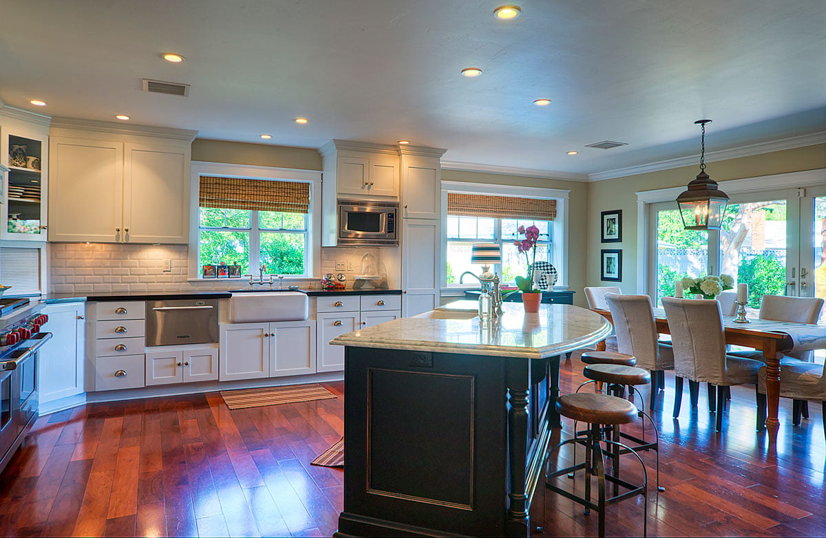 Wide shot of kitchen remodel with dark wood flooring and contrasting white shaker cabinets