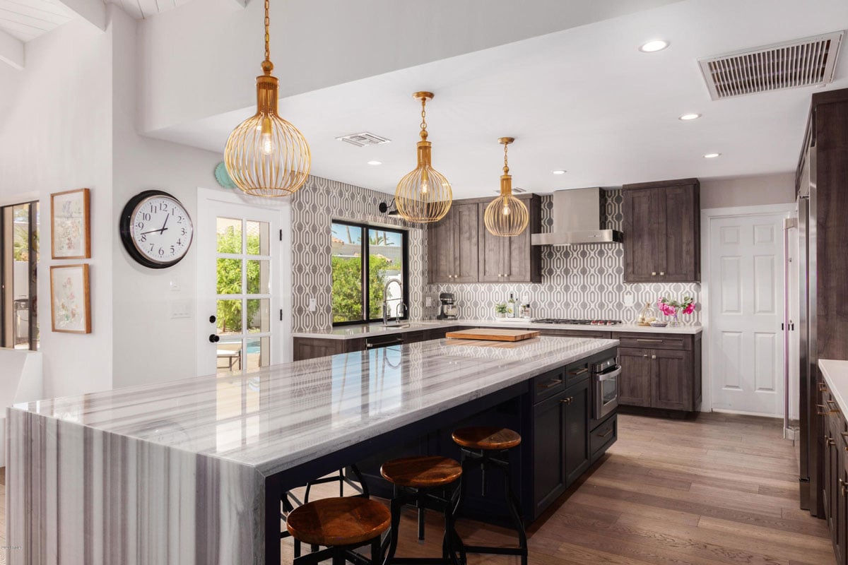 Kitchen island with waterfall countertop accented by golden hanging lights