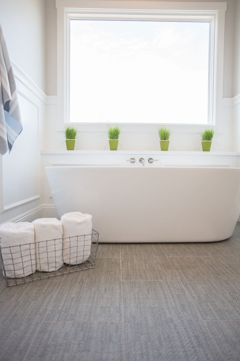 Bathtub against a stained window and rolled up bath towels